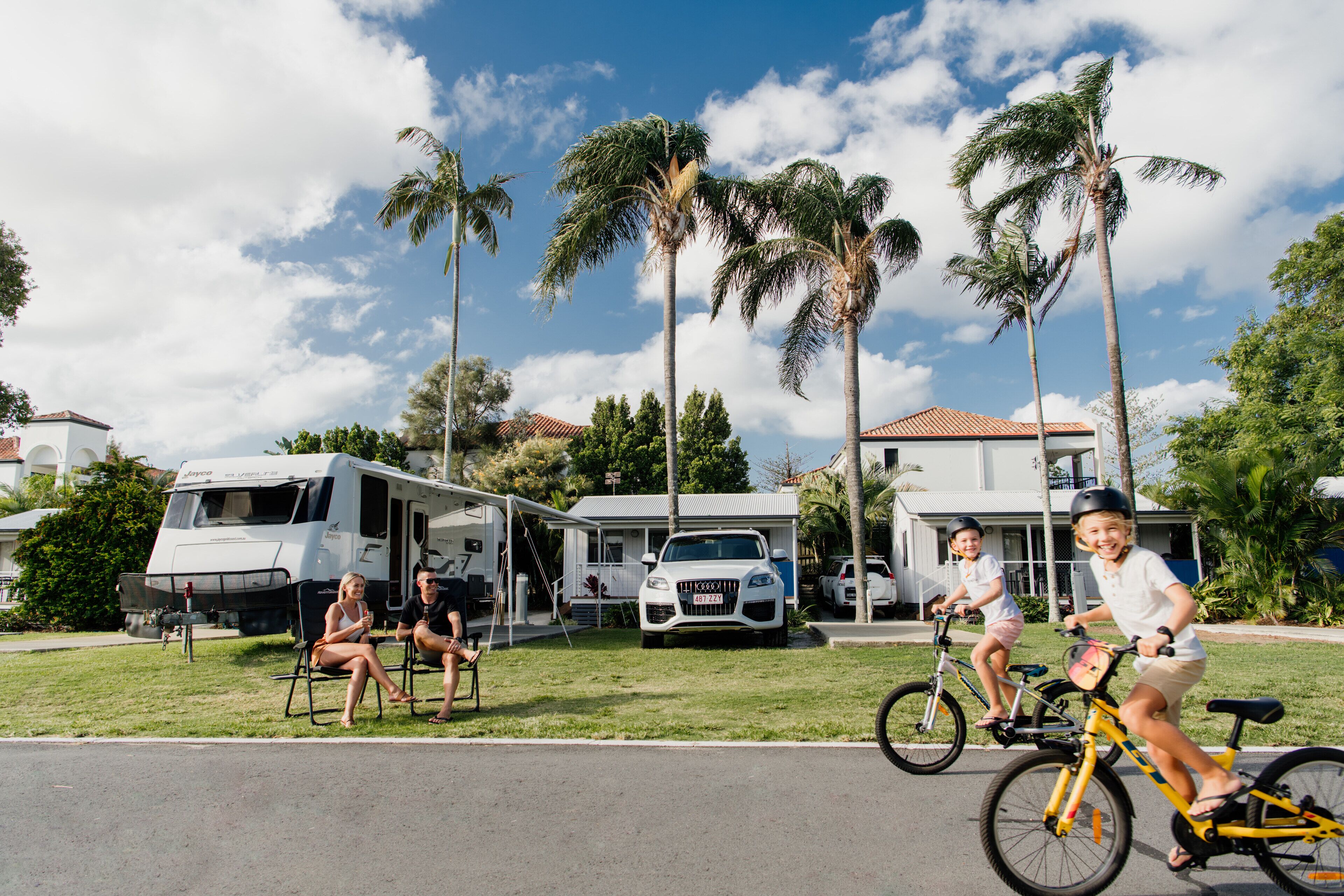 A residential area with RVs parked in front of houses, a street, and palm trees.