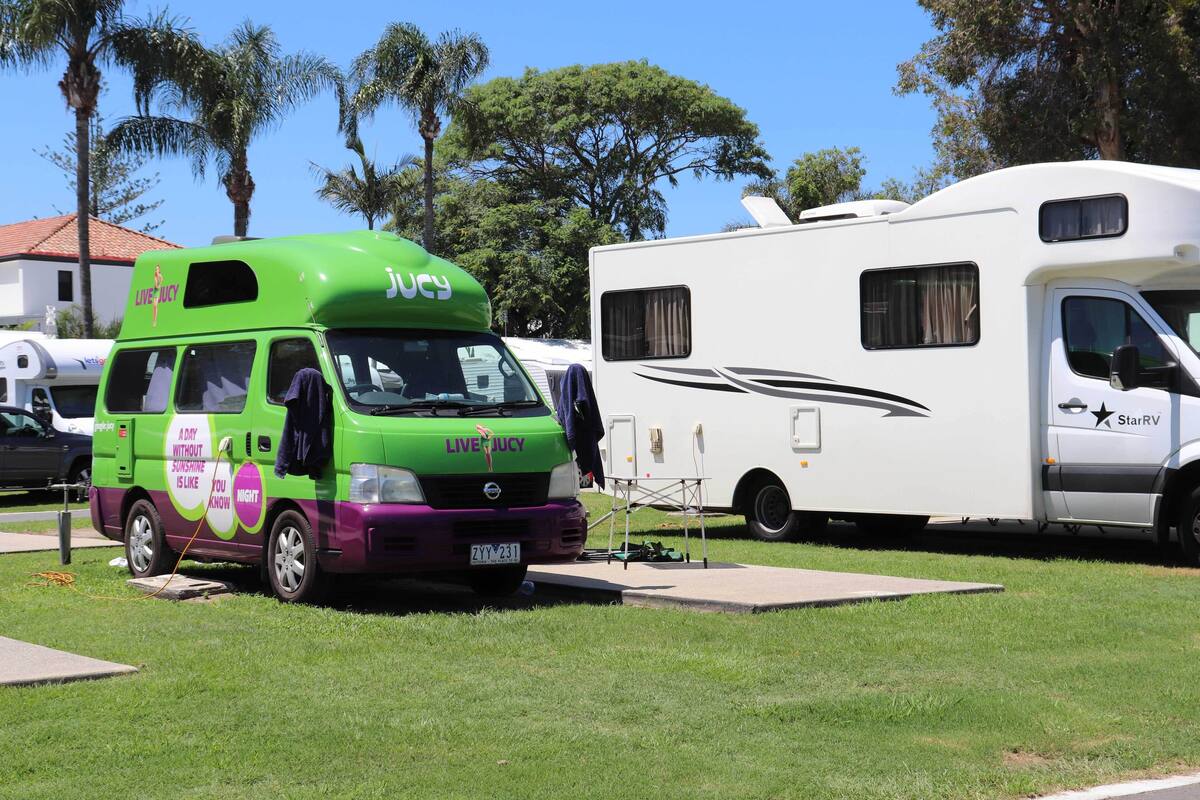 A green and purple van with 'LIVECITY' branding parked next to a white RV.