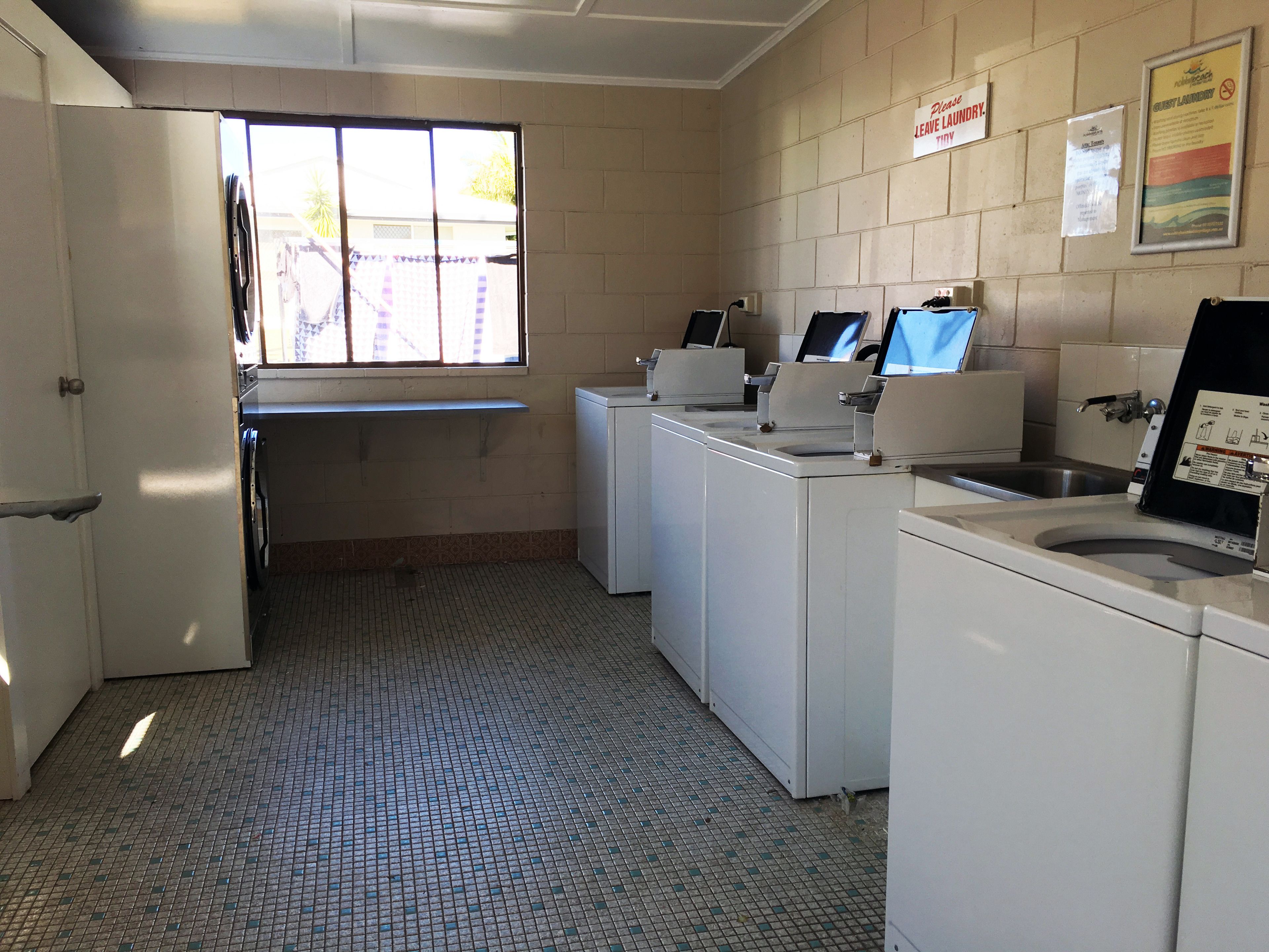 A laundry facility with multiple washing machines and a sink.