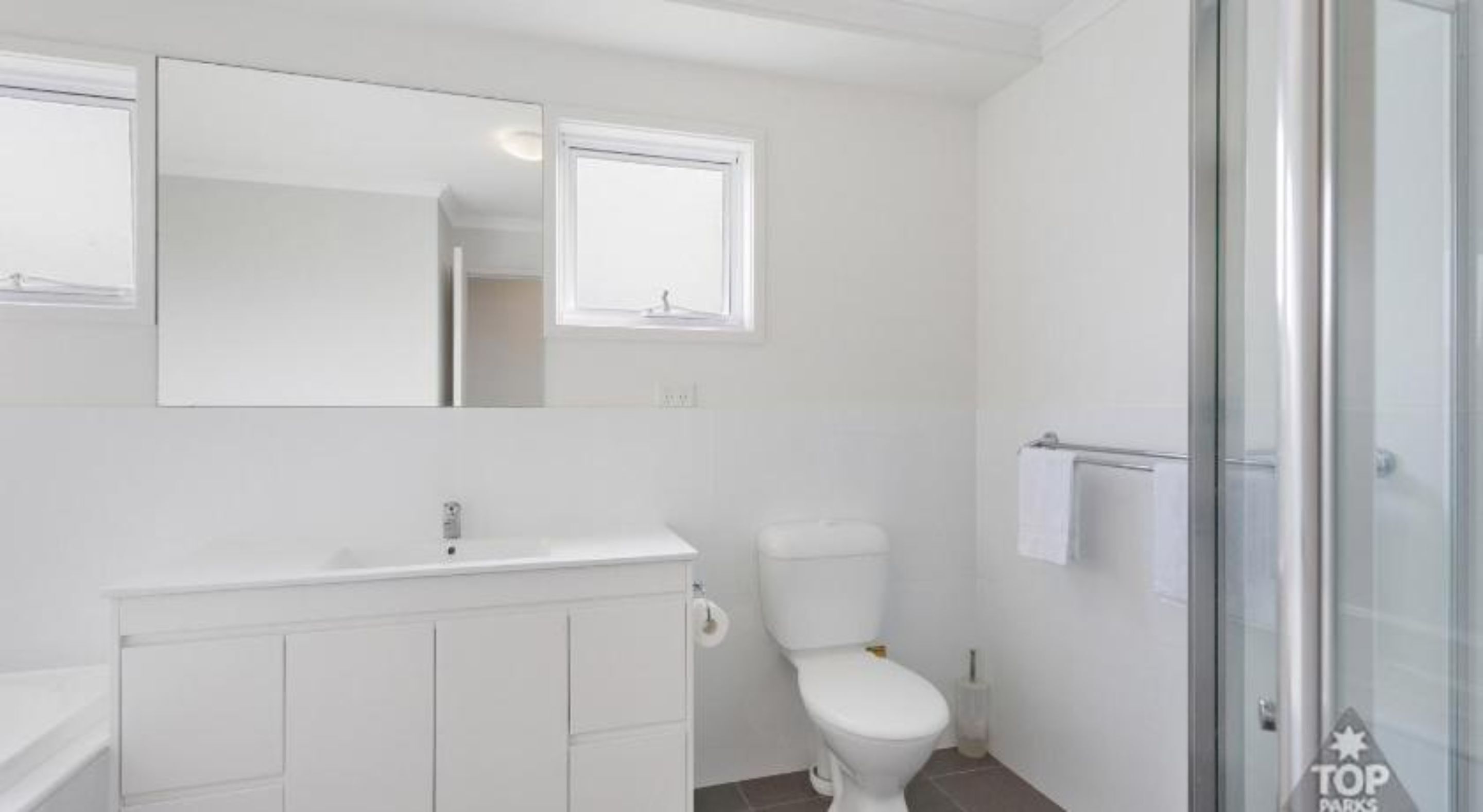 Ein modernes Badezimmer mit Waschbecken, Toilette und Duschbereich in Weiß.