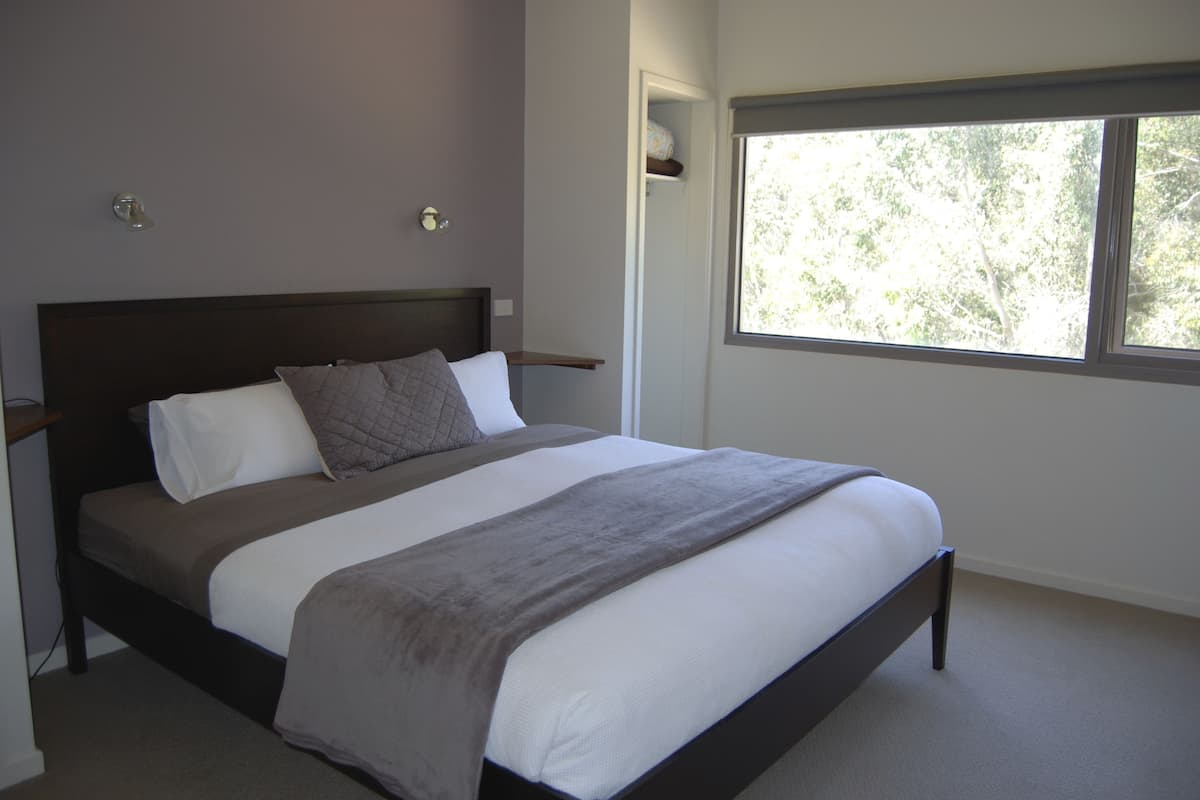 A bedroom with a bed, a window, and a nightstand.