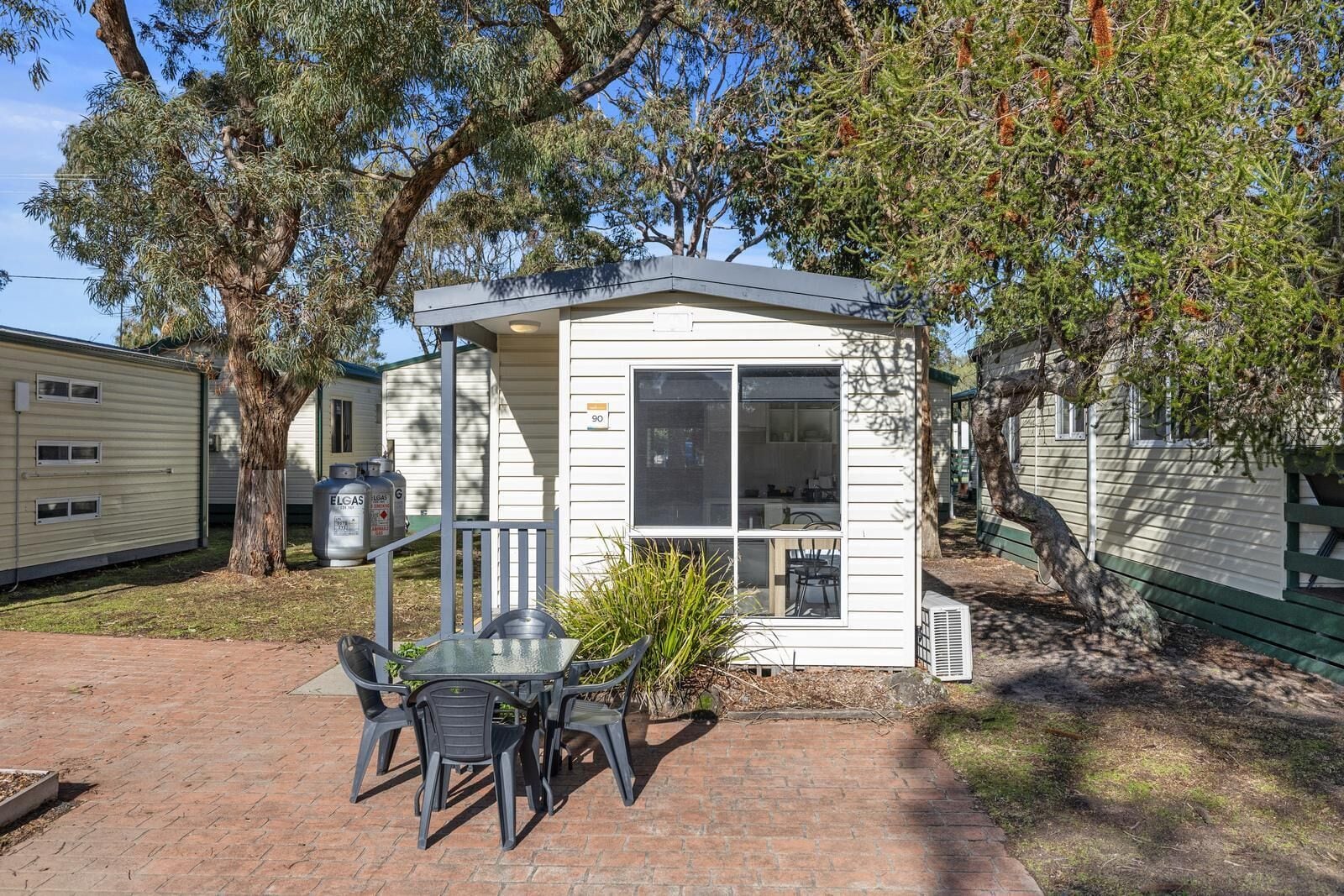 A small, single-story mobile home with a patio area featuring a table and chairs.