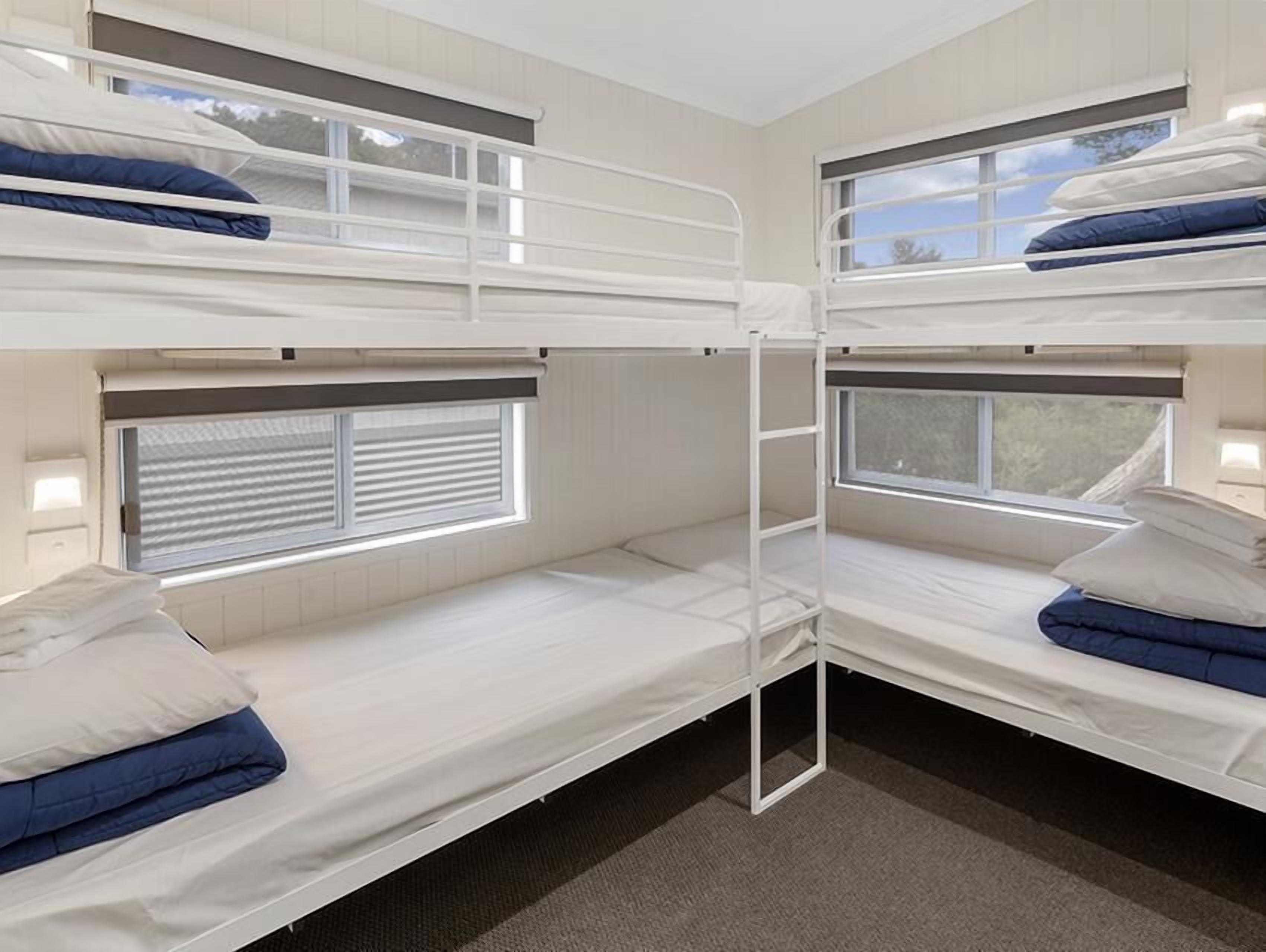 A bunk bed room with two beds, each with a window and a ladder.