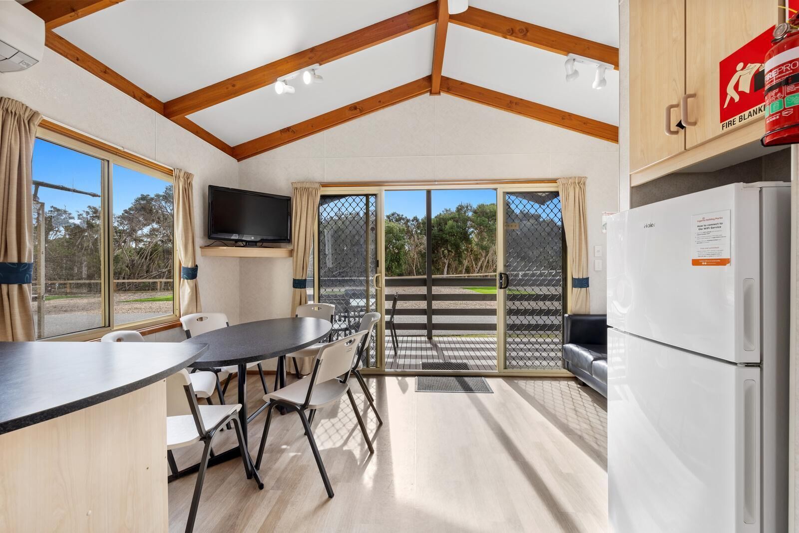 A compact kitchen with a dining area, a television, and a fire extinguisher.