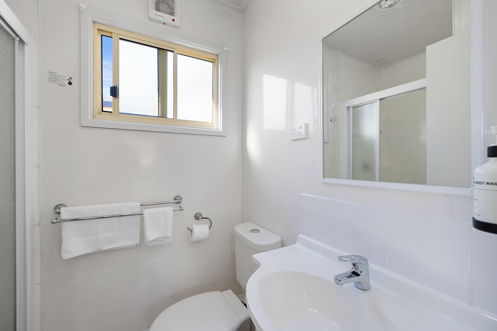 Un baño pequeño y limpio, con inodoro, lavabo y ventana.