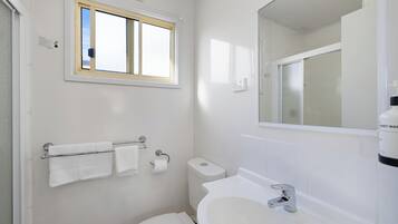 Ein kleines, sauberes Badezimmer mit Toilette, Waschbecken und Fenster.