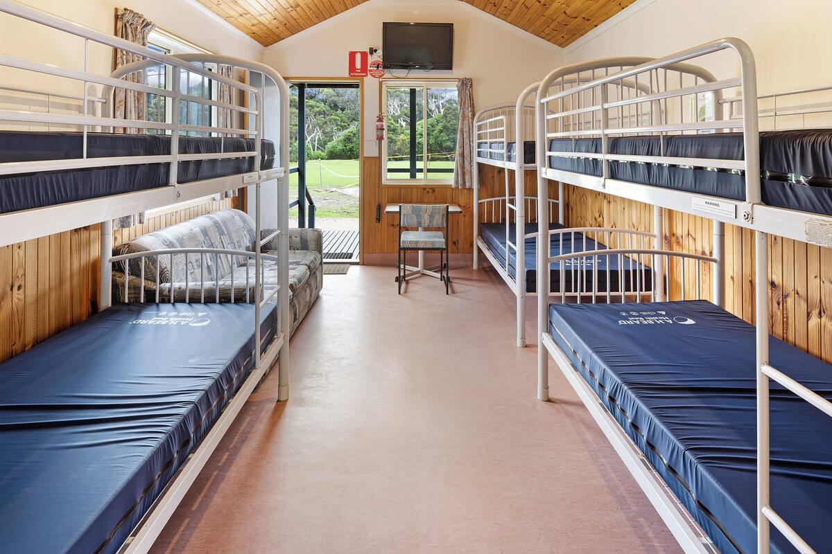 A bunk room with bunk beds, a sofa, and a television.