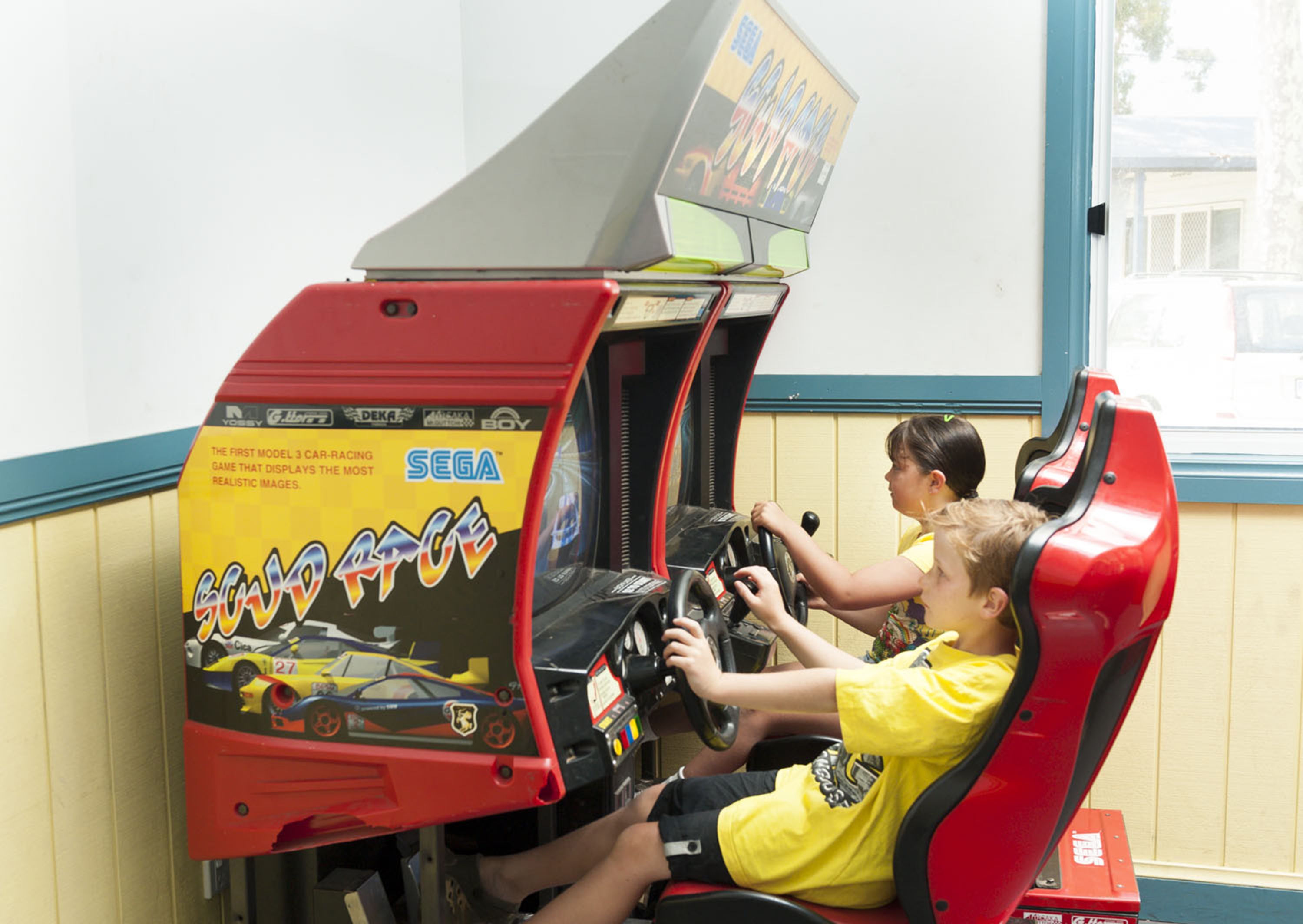 A racing game arcade with two children playing.