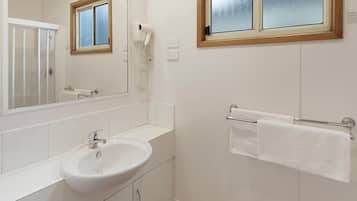 A bathroom with a white sink, a mirror, a towel rack, and a window with frosted glass.