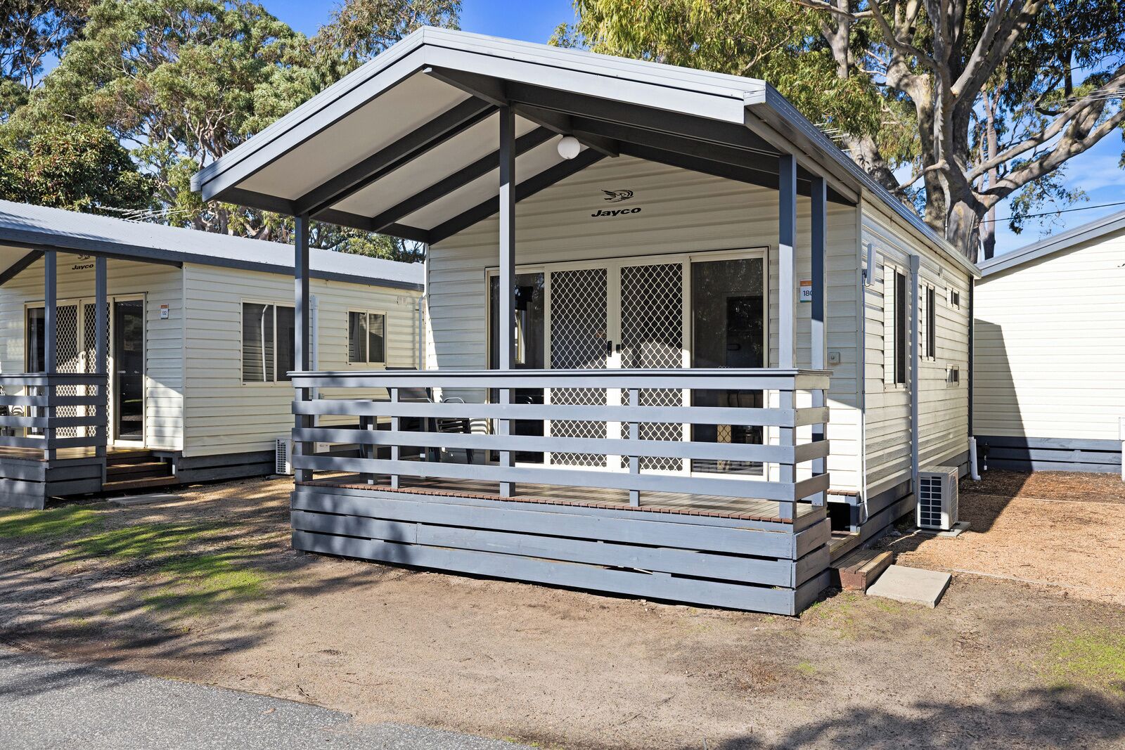 En campingvogn med en overdækket veranda, en indhegnet terrasse og en lille tilhørende garage.