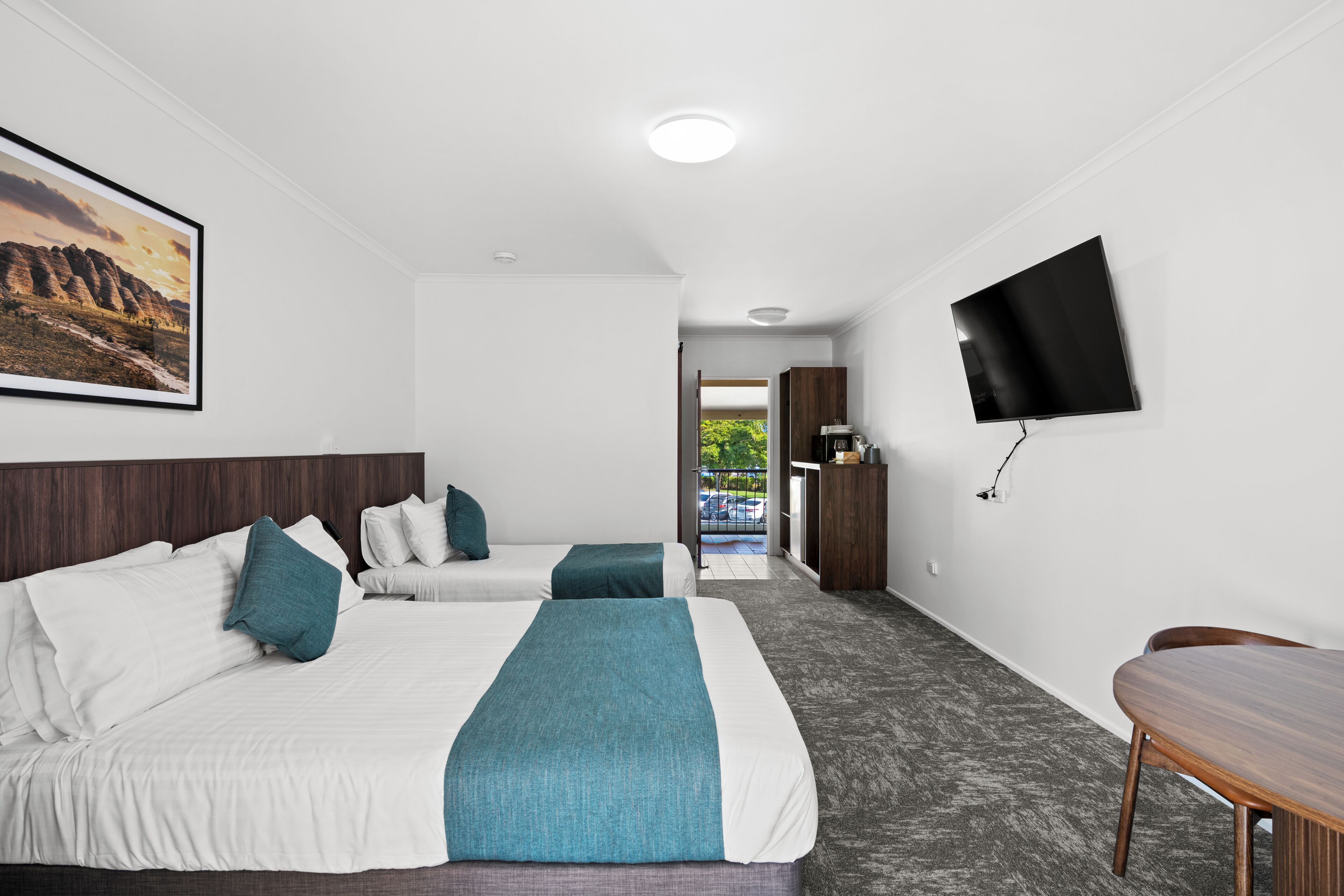 Habitación de hotel con dos camas, un televisor y un escritorio.