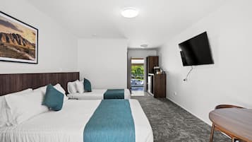 Habitación de hotel con dos camas, un televisor y un escritorio.