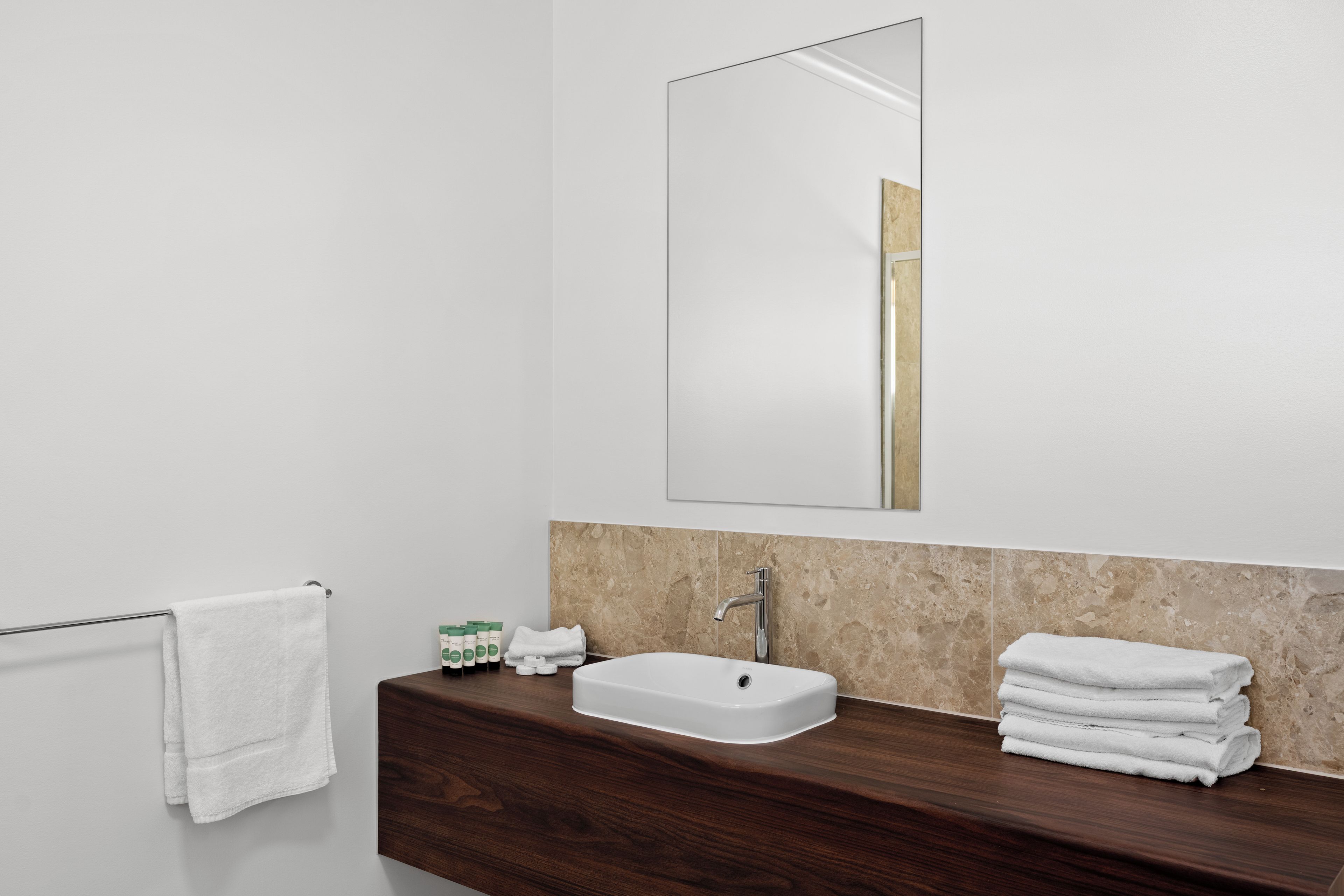 A bathroom with a white sink, a mirror, and a wooden vanity.
