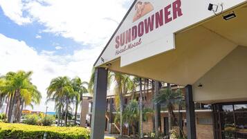 A hotel named 'Sundowner' with a covered entrance, palm trees, and a clear sky.