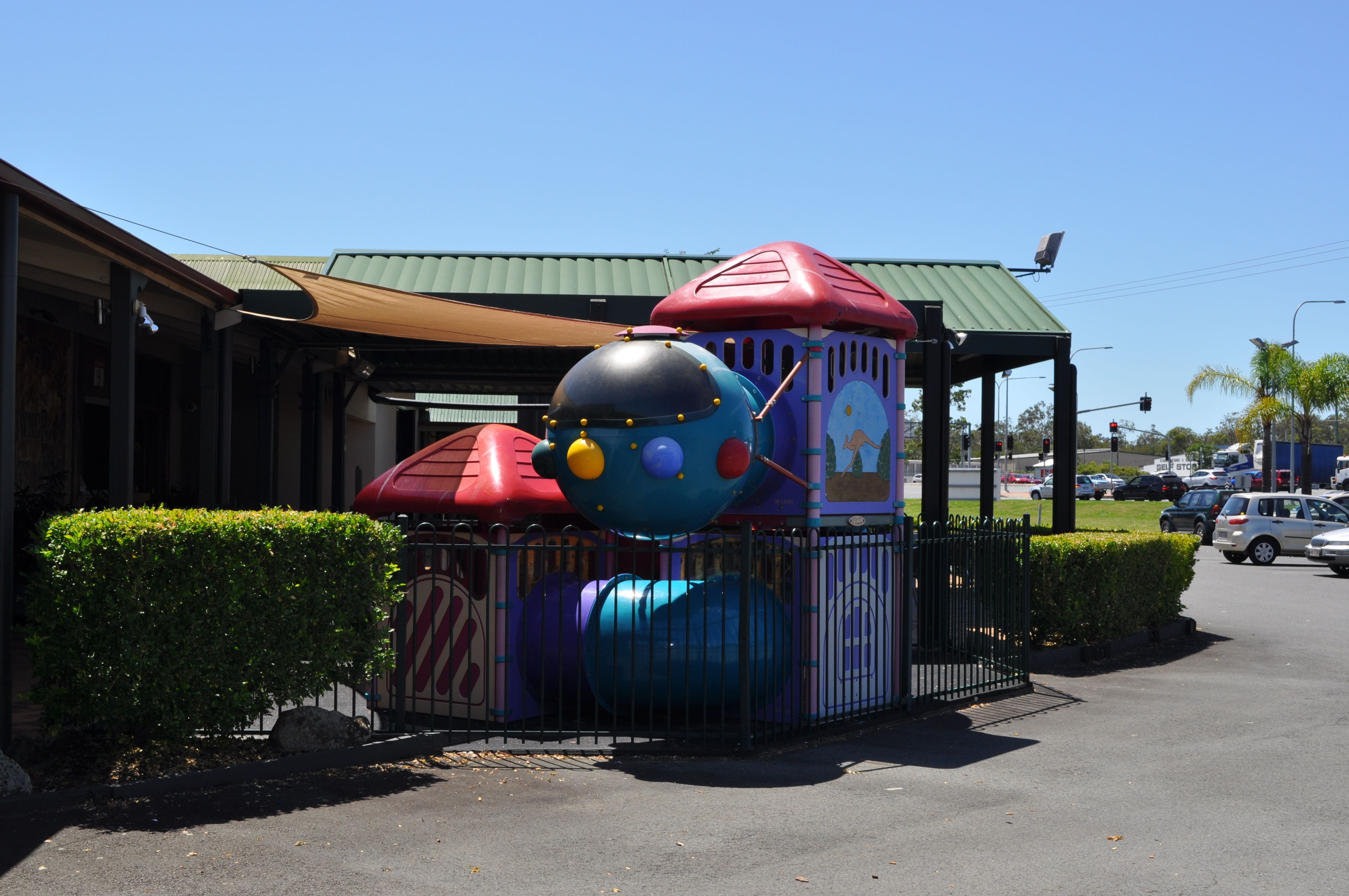 Un parque infantil con estructuras de juego coloridas y una zona de estar cubierta.