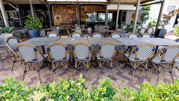 Un espace extérieur aménagé pour les repas, avec un patio couvert, des chaises en osier et une grande table.