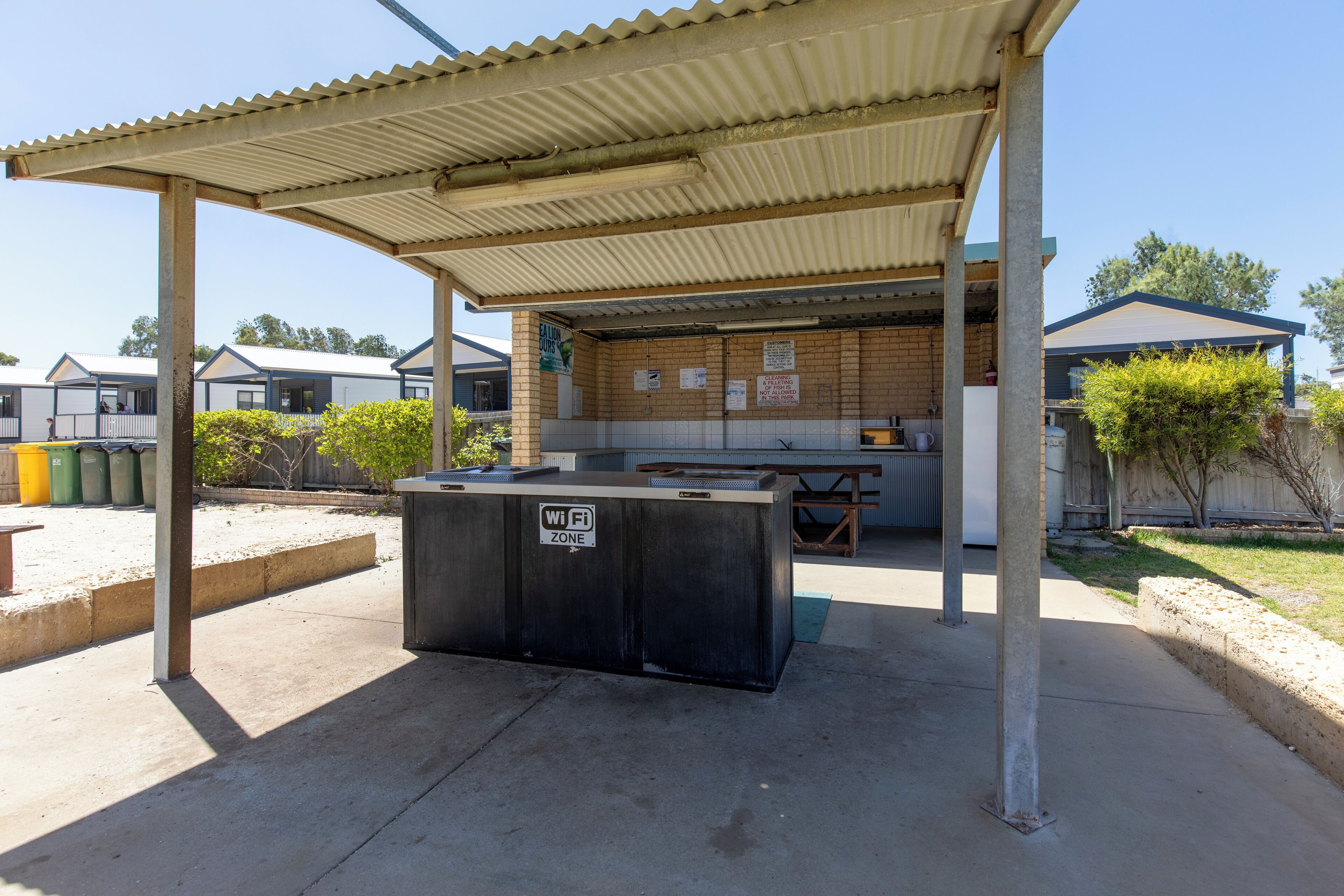 A covered outdoor area with a picnic table and a trash bin labeled "WiFi Zone".
