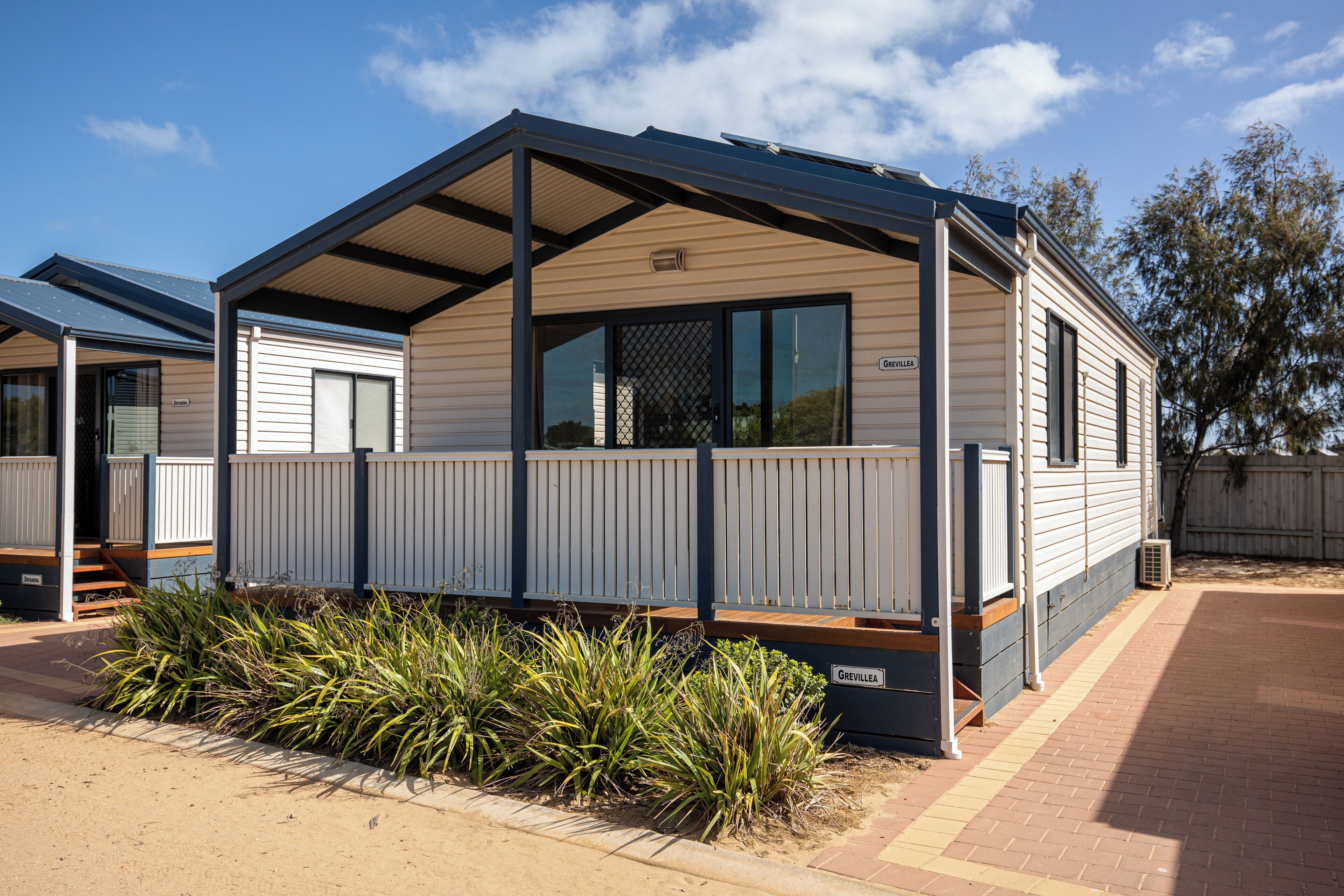 A mobile home with a covered porch, a small garden area, and a brick pathway.