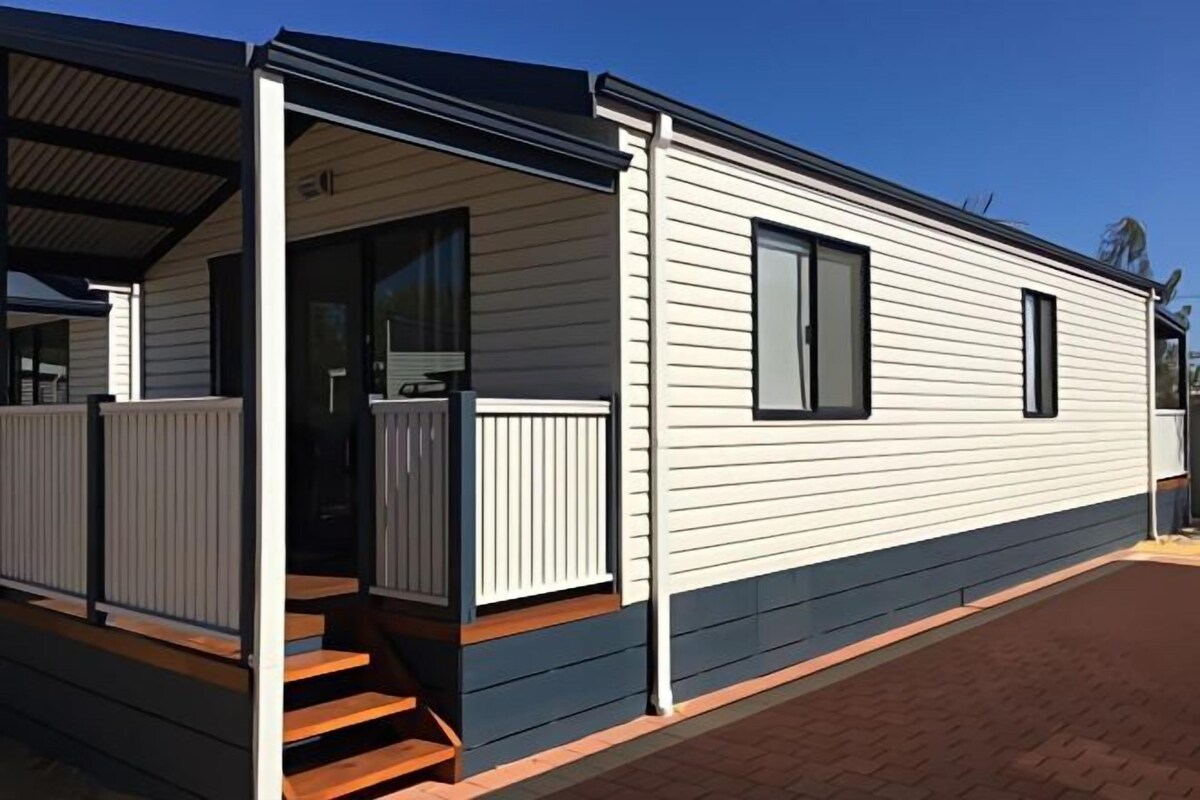 Une maison mobile dotée d’un porche couvert et d’une petite terrasse à l’avant.