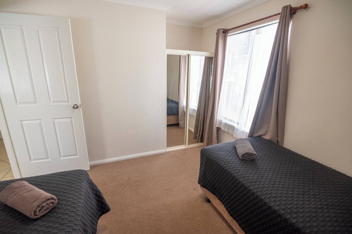 A bedroom with two beds, a door, and a mirror.