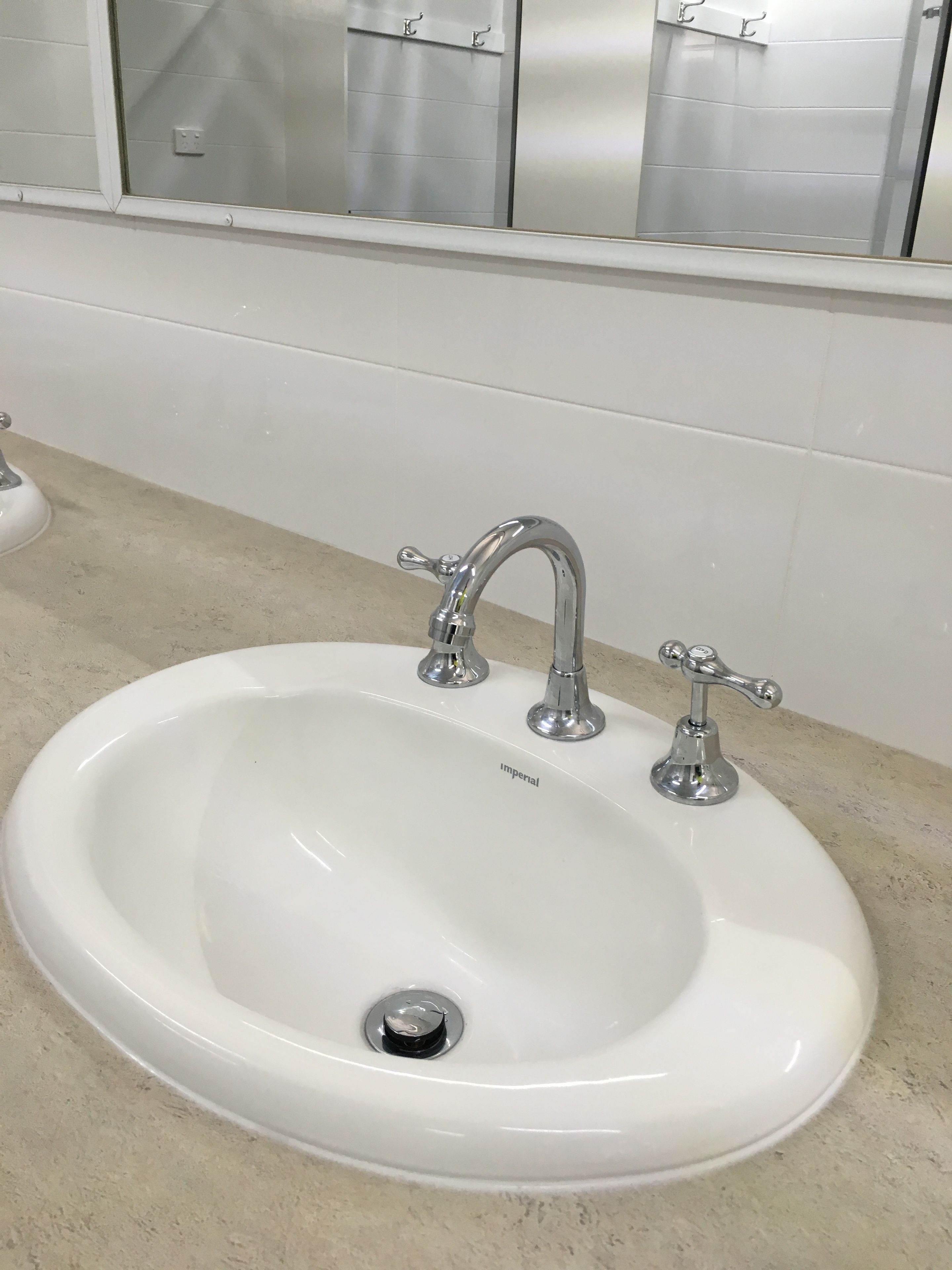 A white bathroom sink with two chrome faucets and a drain.