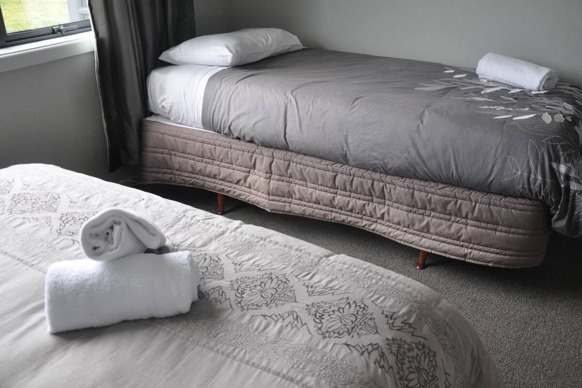 Una cama bien hecha con una colcha acolchada y una toalla enrollada al lado.