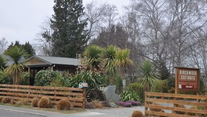 A rustic building with a wooden fence, labeled "Birchwood Cottages," indicating a vacation rental property. - Birchwood Cottages (Te Anau)