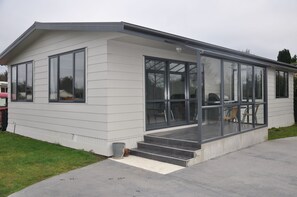 A modern single-story house with large windows, a covered porch, and a concrete driveway. - Birchwood Cottages (Te Anau)