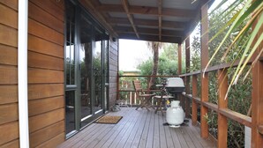 A wooden deck with a grill and outdoor furniture. - Birchwood Cottages (Te Anau)