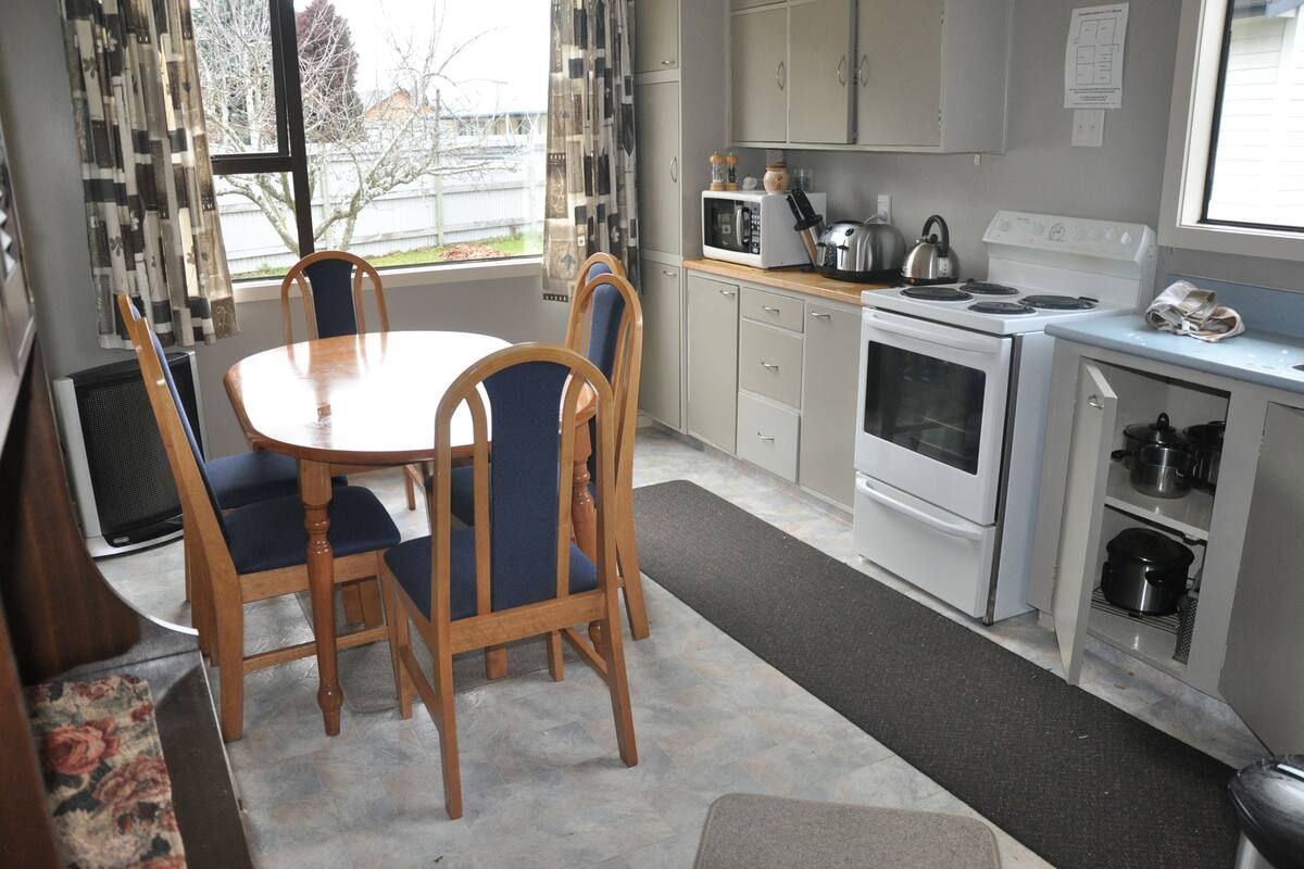 Una cocina compacta con una mesa y sillas, microondas, estufa y armarios.