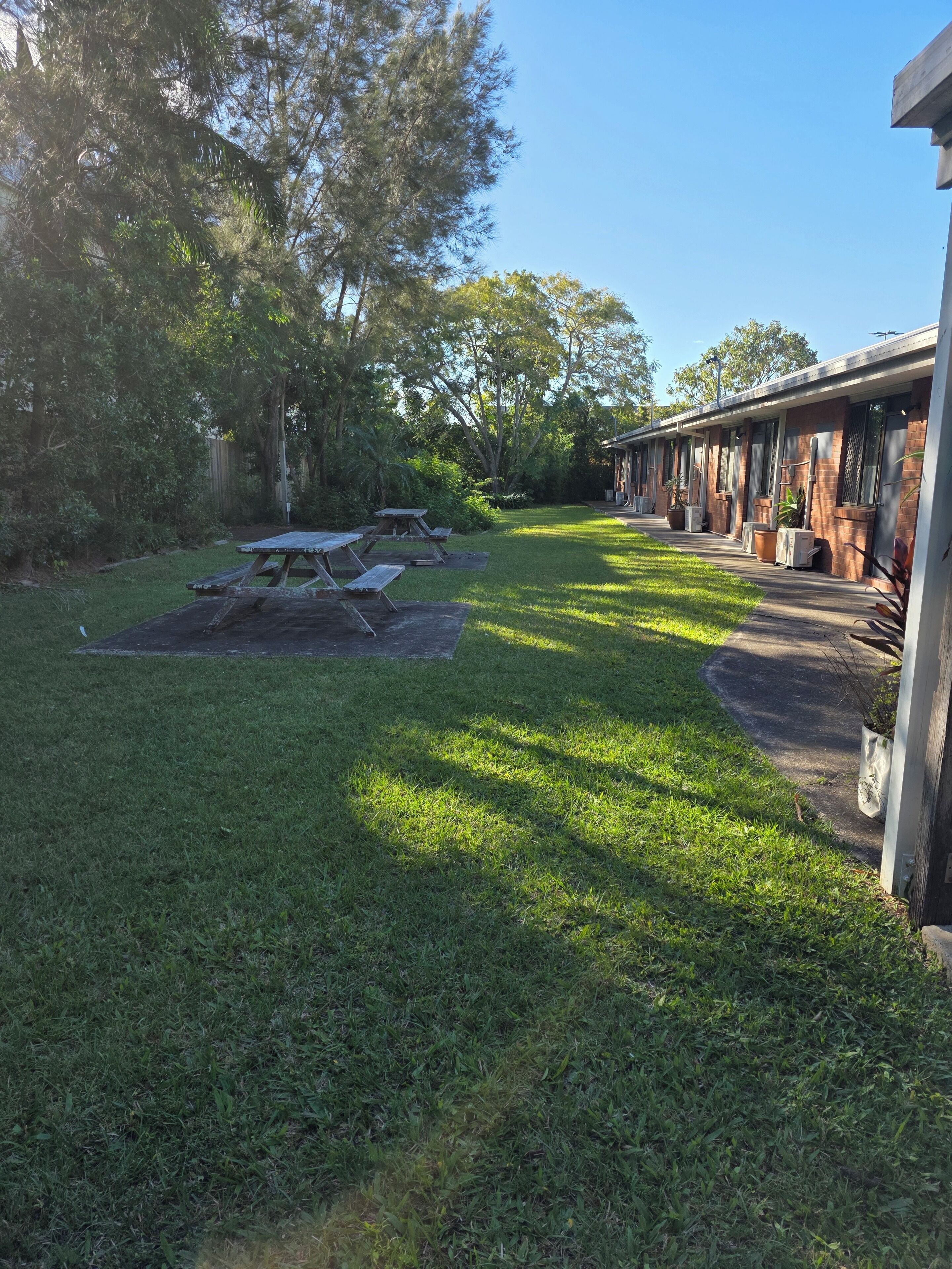A grassy yard with picnic tables and a building with a brick facade.