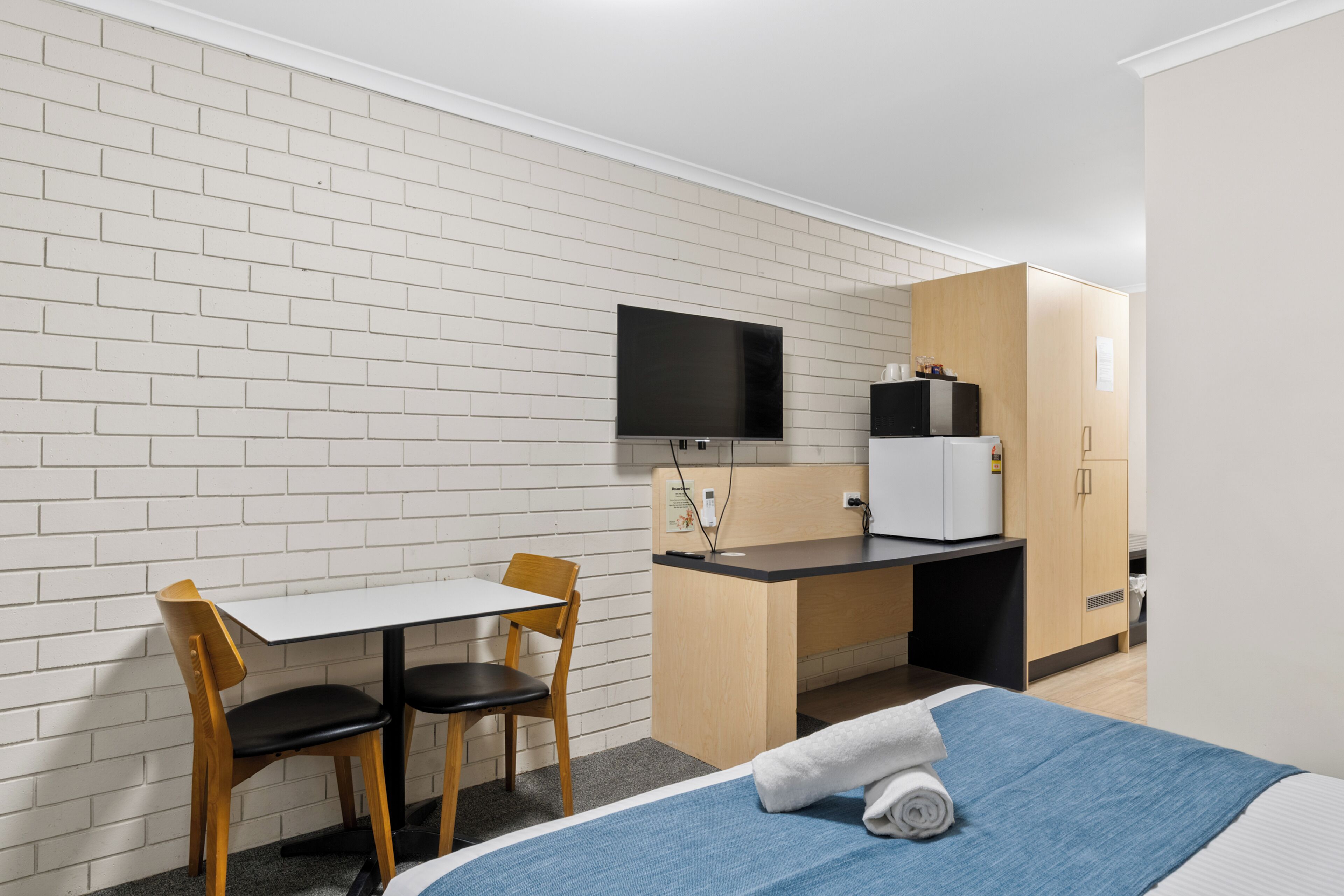 A hotel room with a bed, a desk, a TV, and a wardrobe.