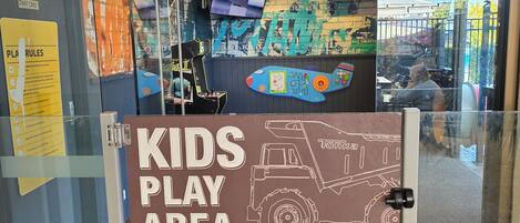 Une entrée avec une porte en verre, sur laquelle on peut lire les inscriptions suivantes : « ESPACE DE JEUX POUR ENFANTS », « RÉSERVÉ AU PERSONNEL » et « RÈGLES DU JEU ».