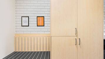 Une pièce comprenant un lit, une armoire en bois et deux documents encadrés accrochés à un mur en briques.