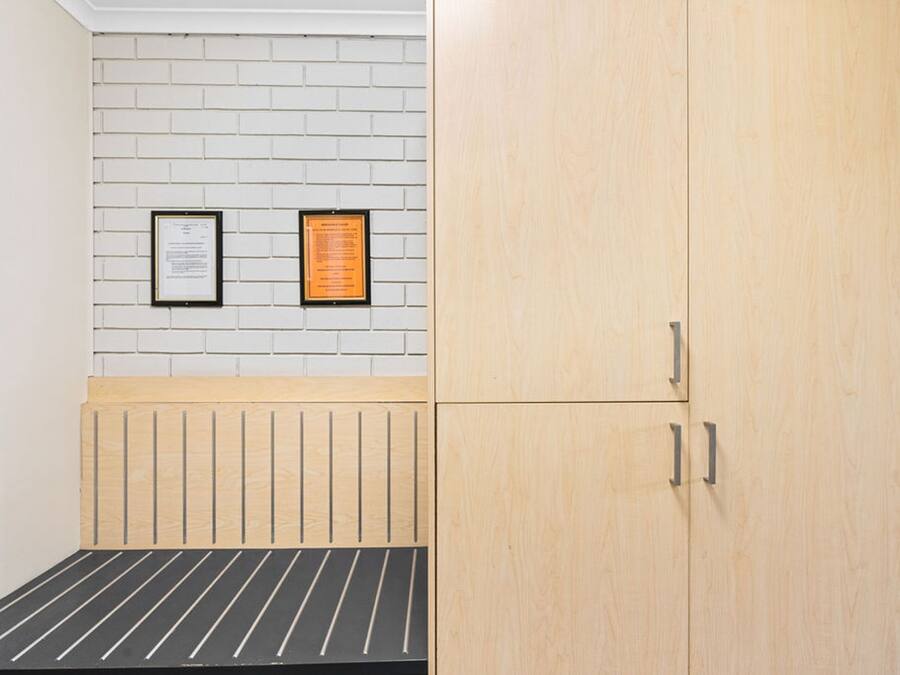 Une pièce comprenant un lit, une armoire en bois et deux documents encadrés accrochés à un mur en briques.