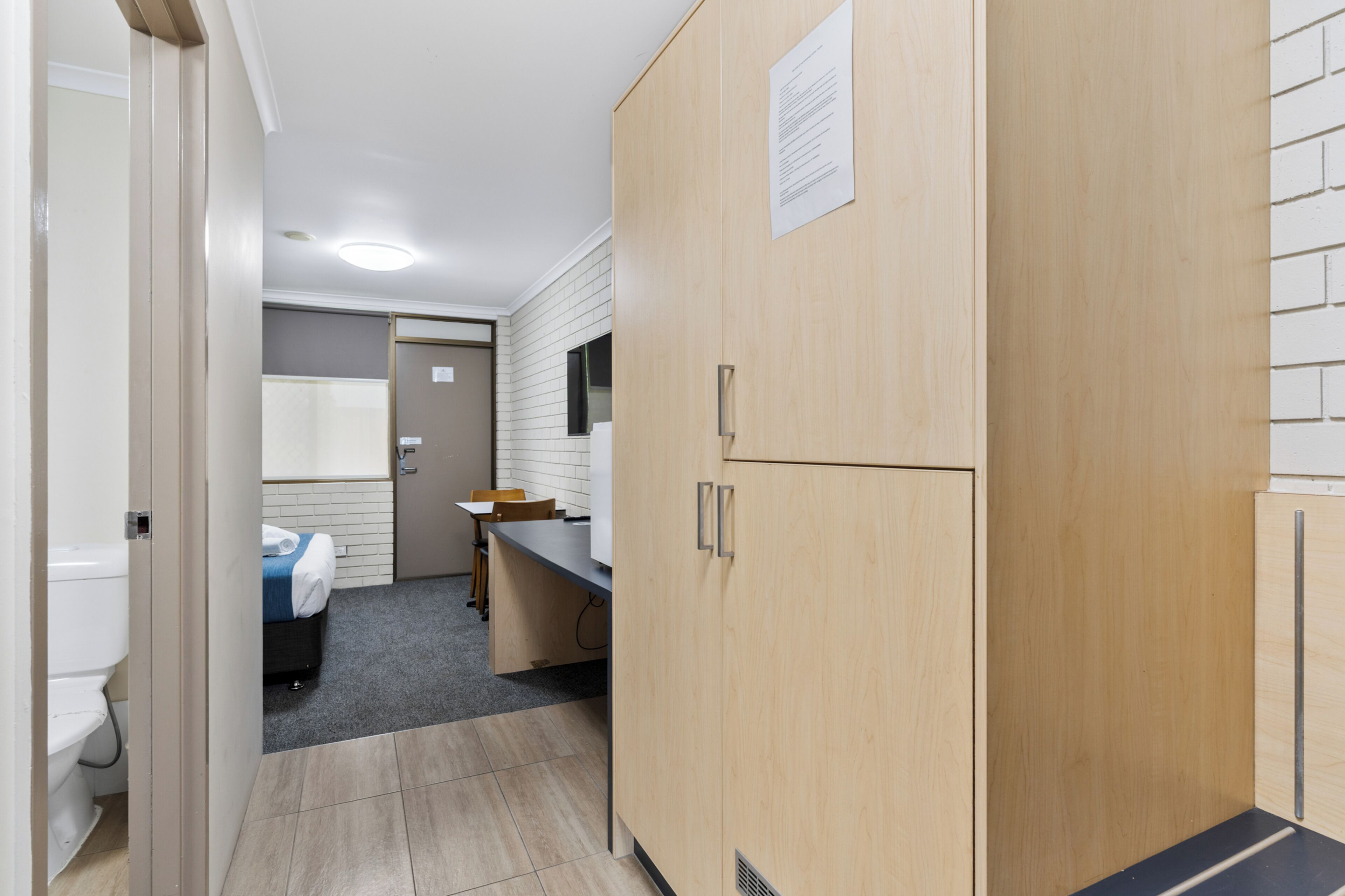 Una camera d'albergo compatta con bagno, angolo cottura e una piccola zona pranzo.