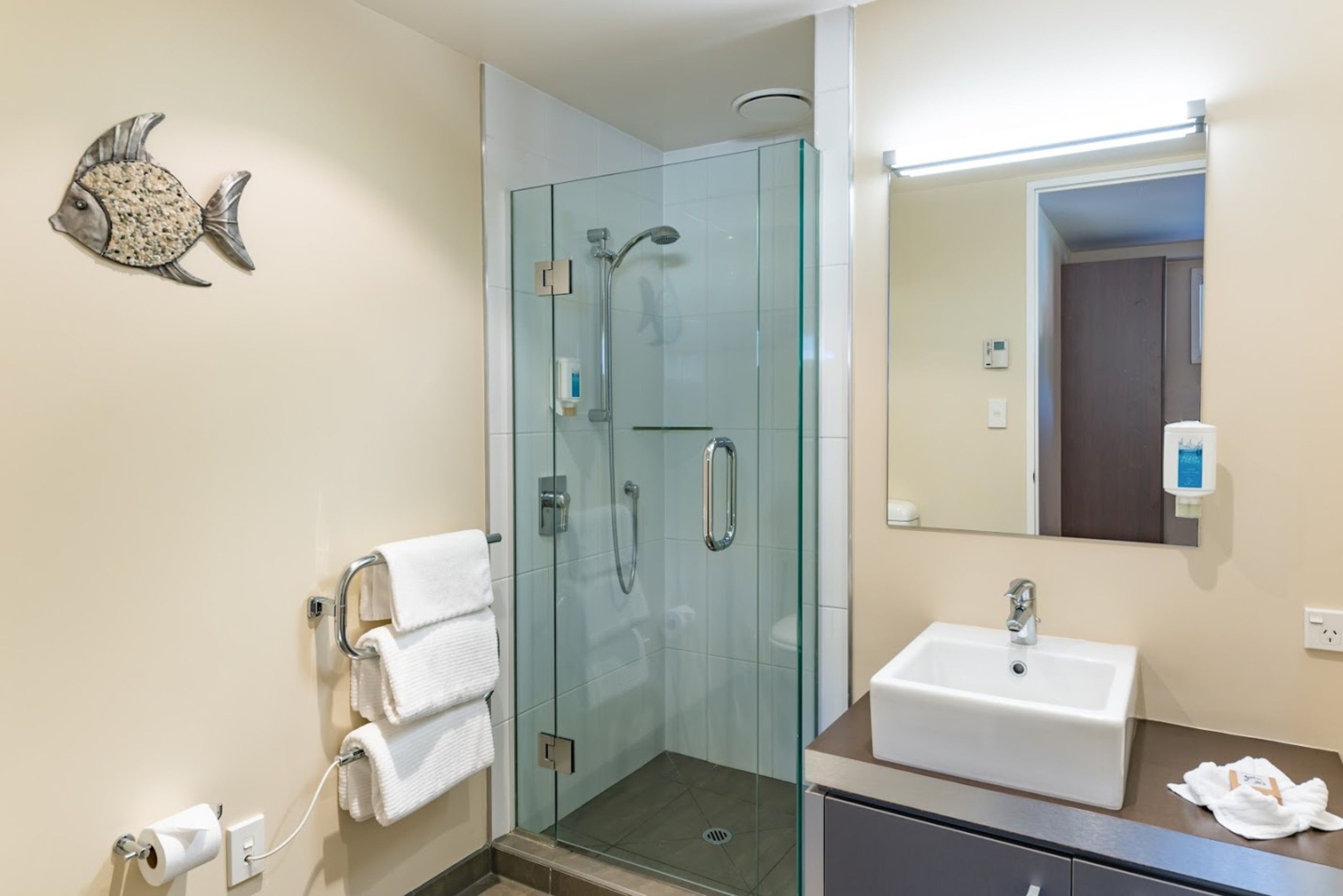 Een moderne badkamer met een douche met glazen wand, een wastafel en een handdoekrek.
