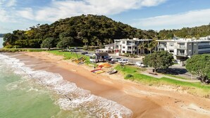 A beachfront hotel with a view of the ocean and a hill in the background. - Edgewater Palms Apartments (Paihia)