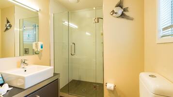 A modern bathroom with a glass-enclosed shower, a white sink, and a toilet.