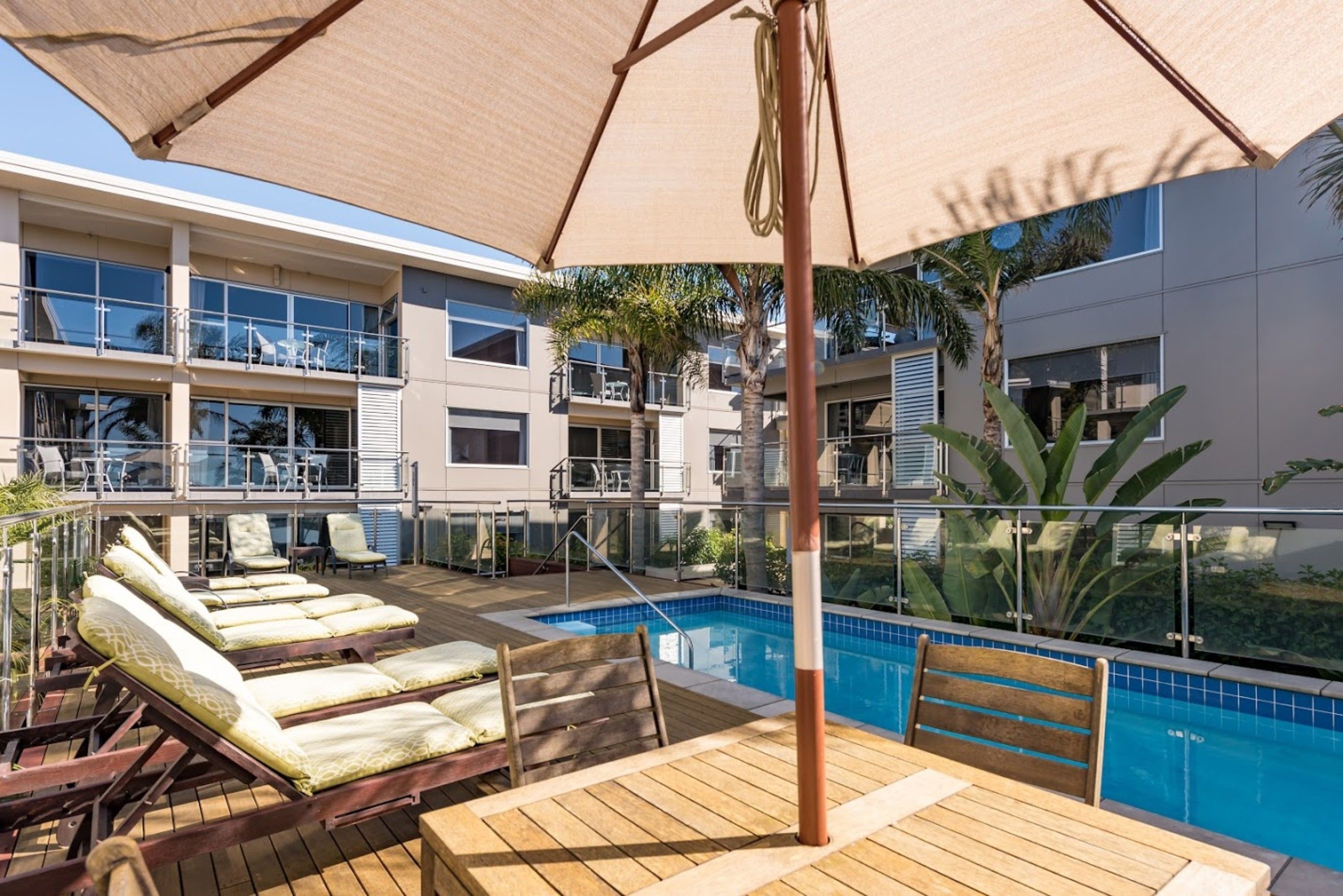 A poolside area with lounge chairs, a wooden deck, and a pool.