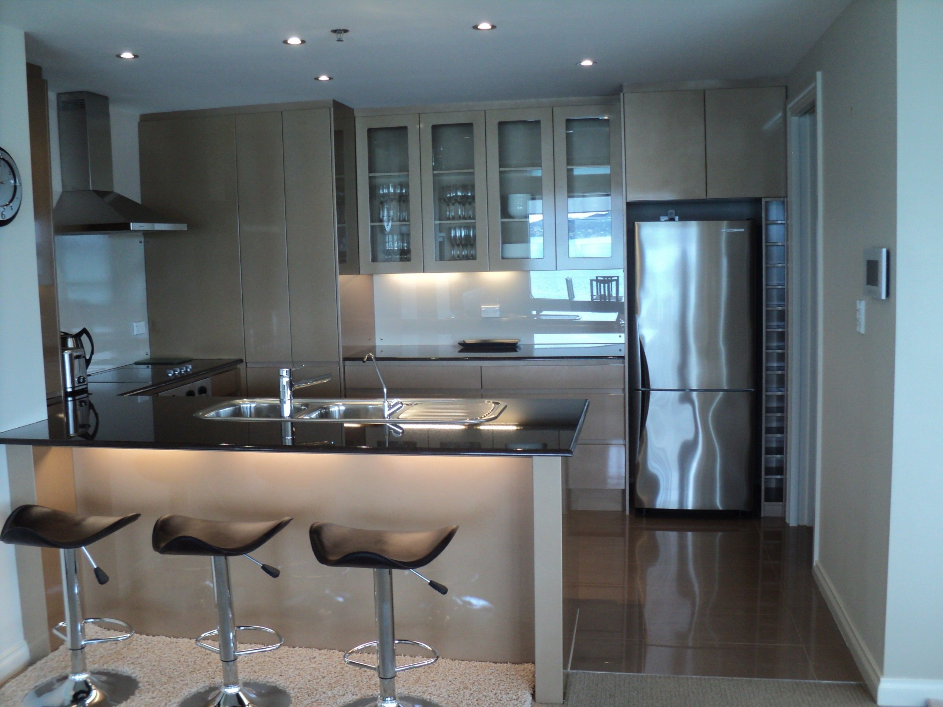 A modern kitchen with a central island, stainless steel appliances, and a bar area with stools.