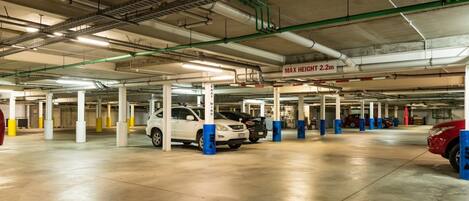 Eine unterirdische Parkgarage mit mehreren Ebenen, Betonpfeilern und Deckenbeleuchtung.