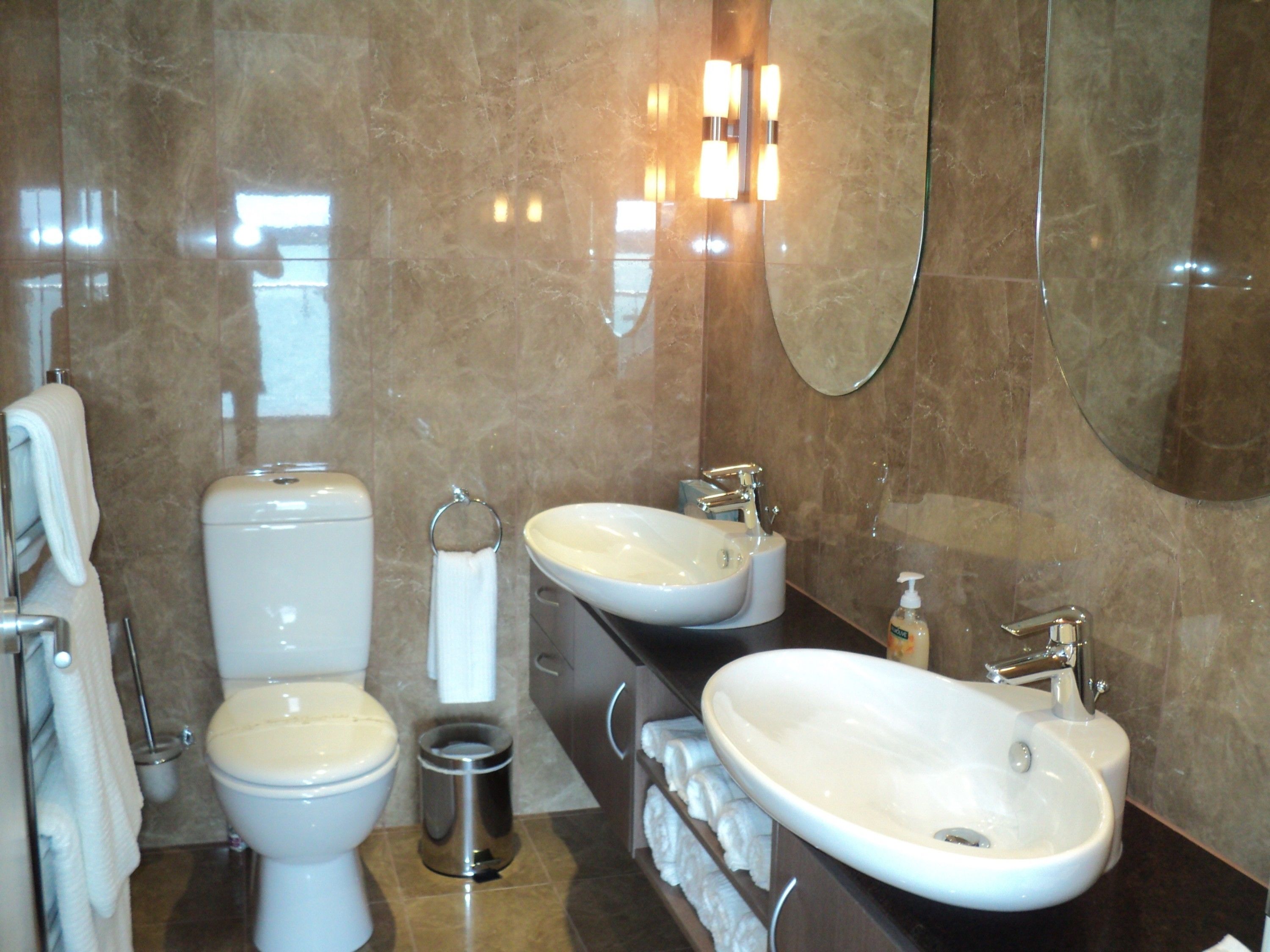 A modern bathroom with a toilet, bidet, sink, and a large mirror.