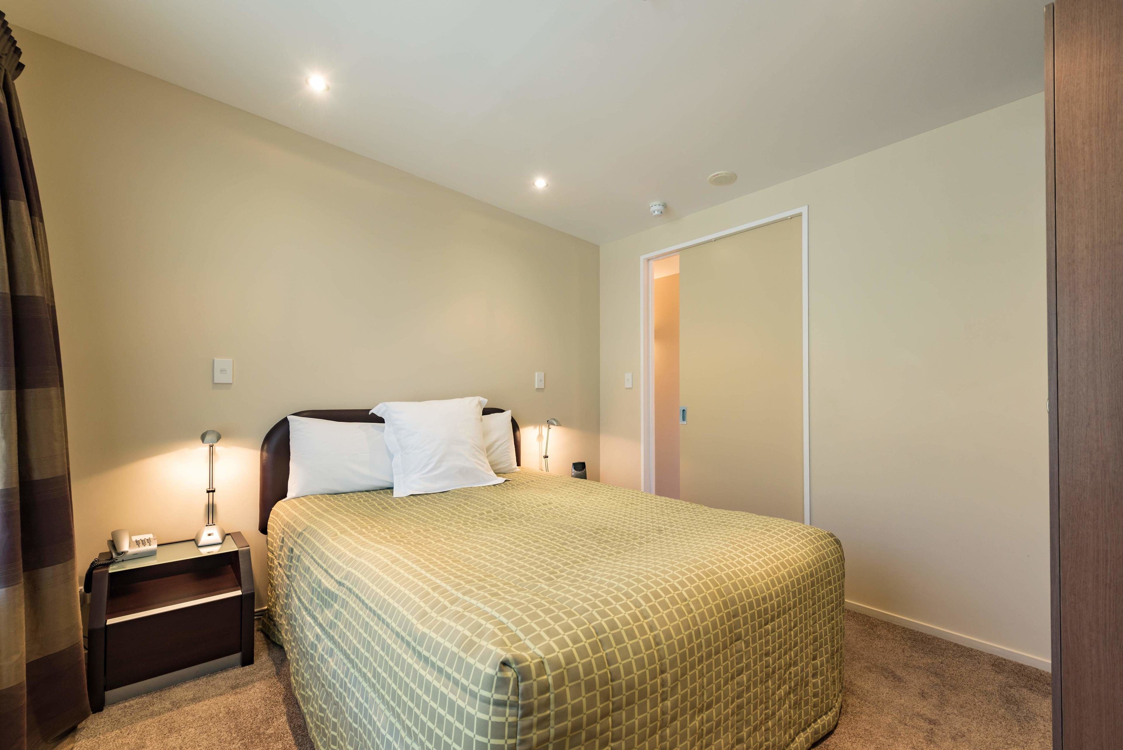 A neatly arranged bedroom with a bed, bedside tables, and a door.