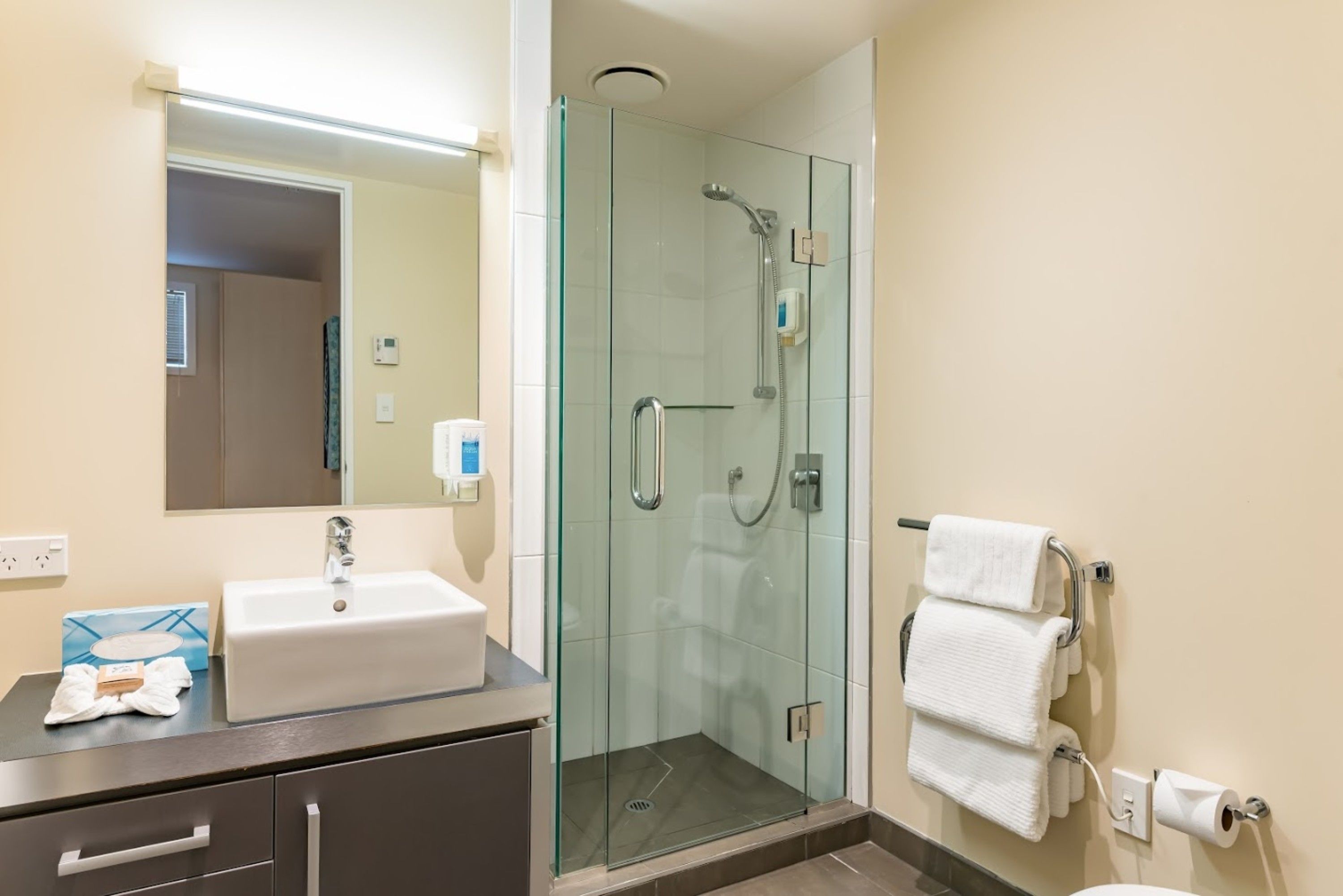 A modern bathroom with a glass-enclosed shower, a sink, and a toilet.