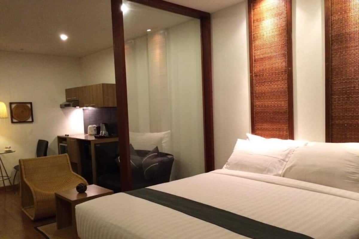 Una habitación de hotel con una cama grande, un escritorio con una silla, una mesita y un espejo.