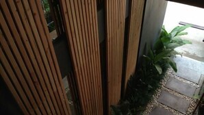 A wooden fence with vertical slats, a stone pathway, and lush green plants. - 5ive Beach House Hotel (Pattaya)