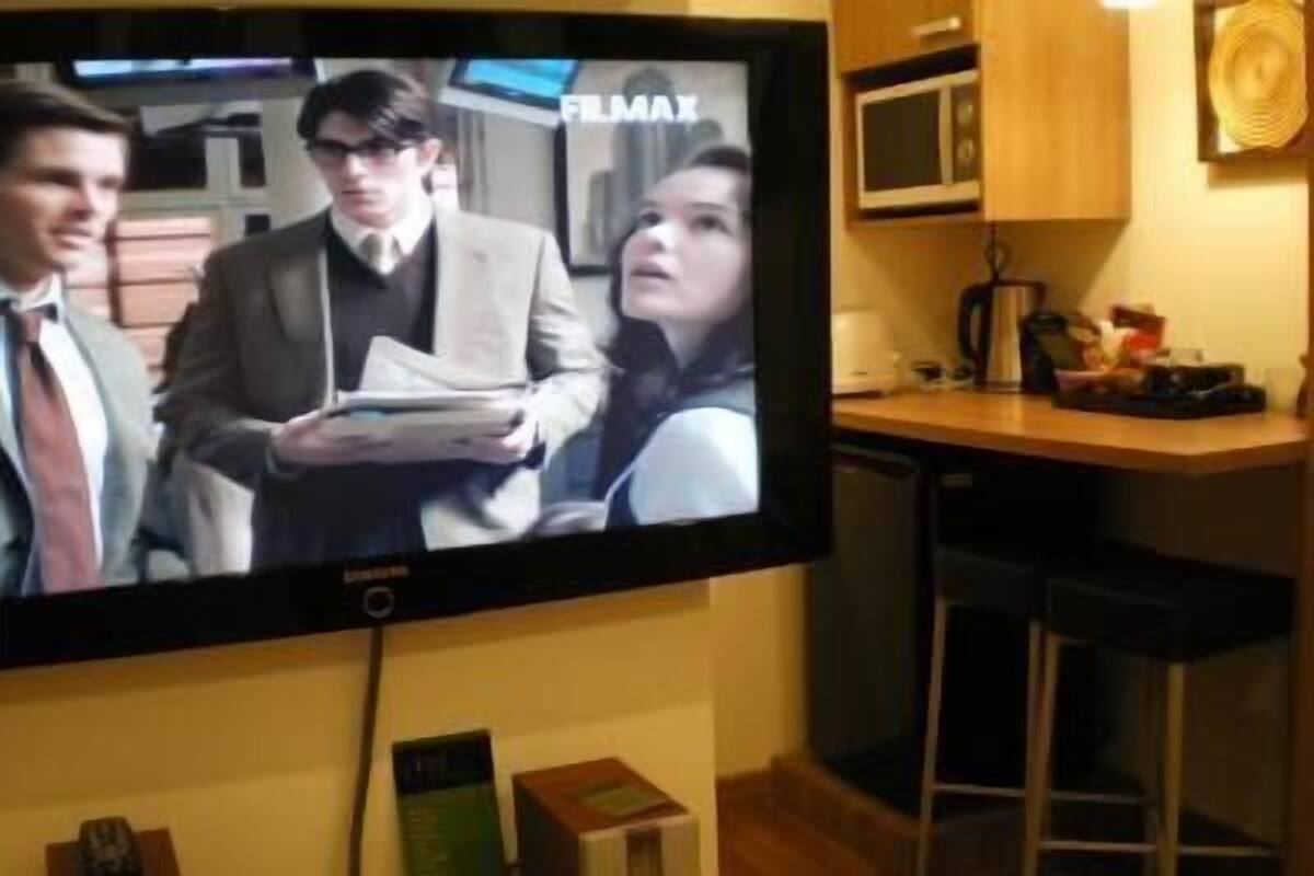 Un televisor instalado en una pared mostrando una escena de película.