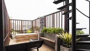 A modern balcony with a wooden floor, black metal railing, and potted plants. - 5ive Beach House Hotel (Pattaya)