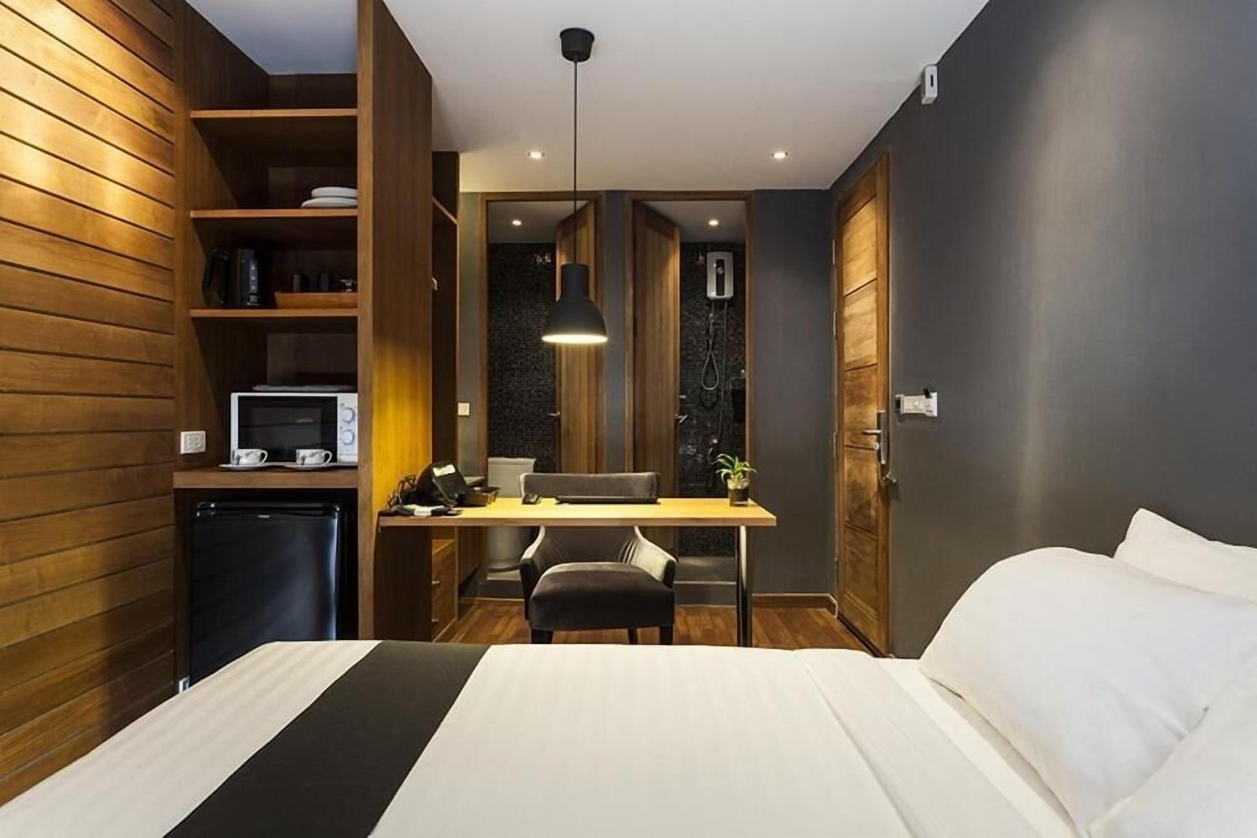 Una habitación pequeña con cama, escritorio y una kitchenette.
